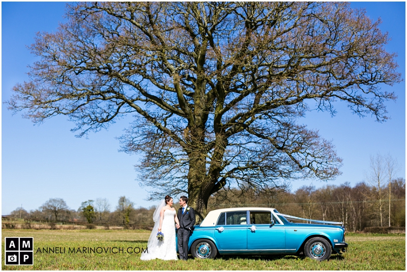"wedding-couple-in-a-field-with-wedding-car"