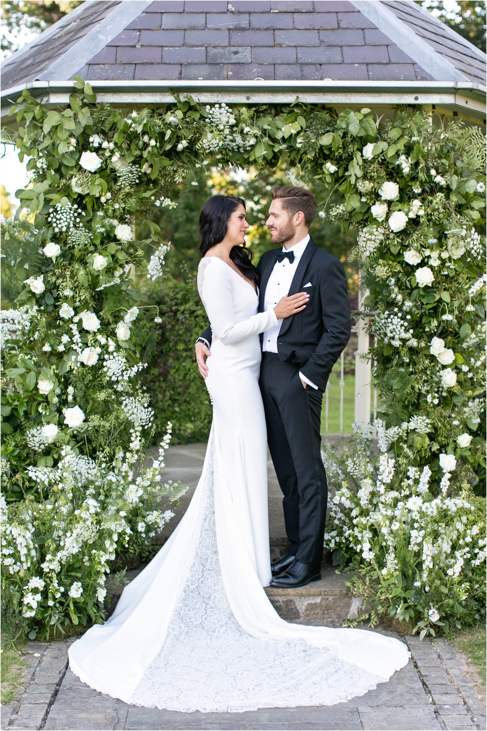 Elegant wedding couple standing in a flower arch at Lemore Manor