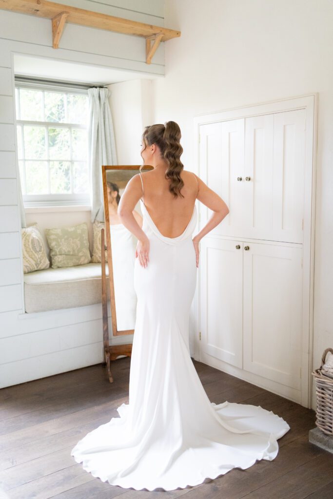 A pretty bride in a backless wedding gown shortly before her outdoor wedding at Middleton Lodge